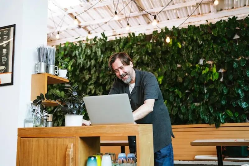 Dueño de un negocio local en Argentina revisando métricas de marketing digital en una notebook dentro de su comercio